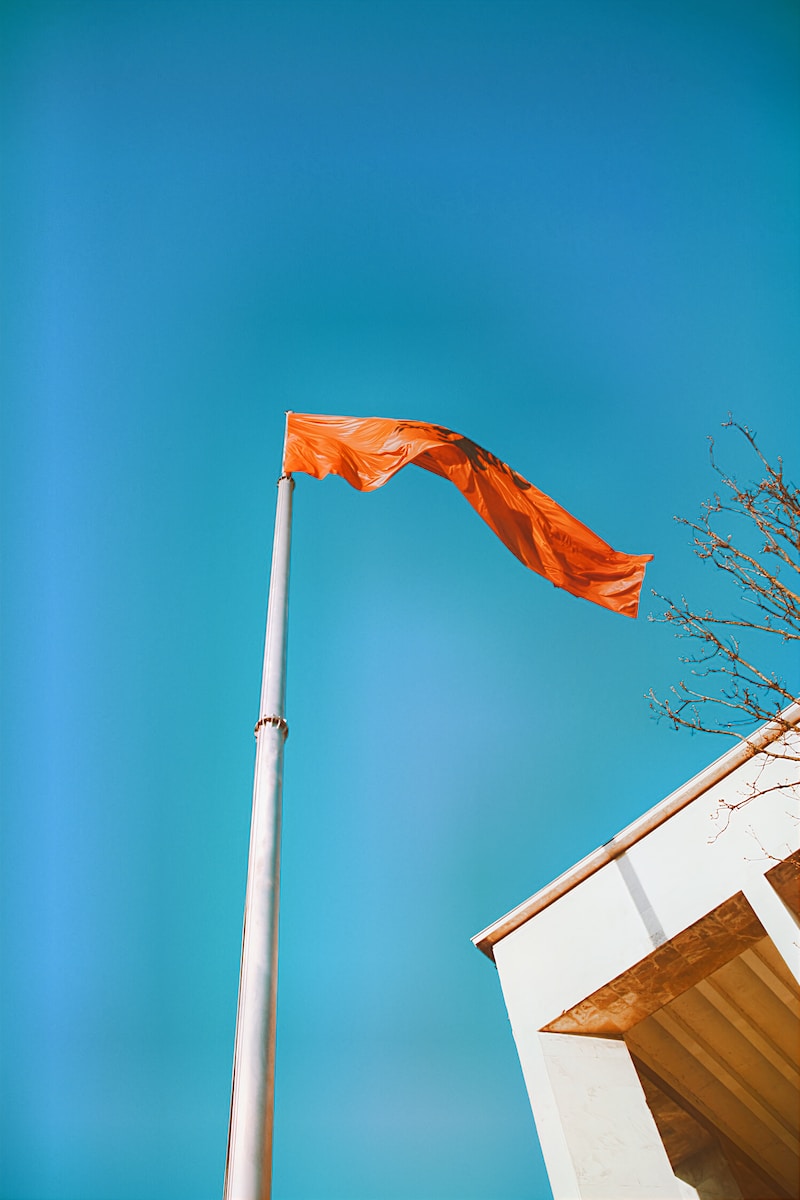 an orange flag is flying high in the sky